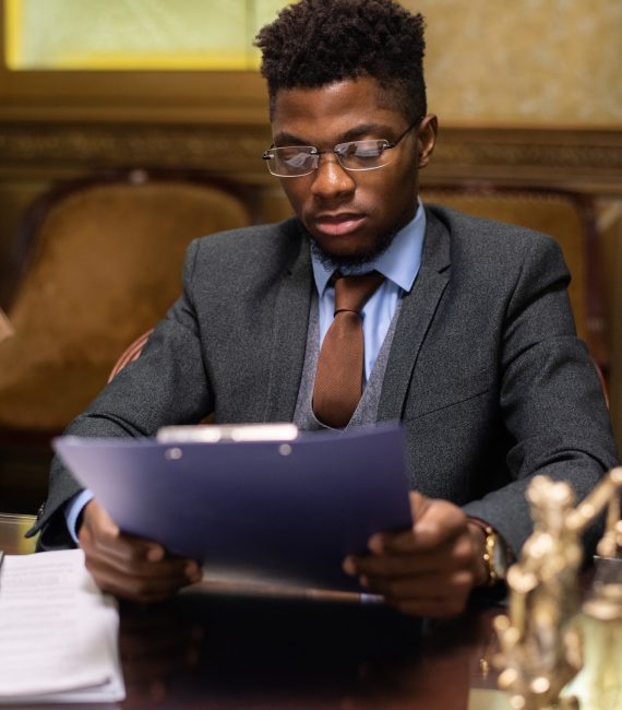 Young successful lawyer of African ethnicity looking through juridical document